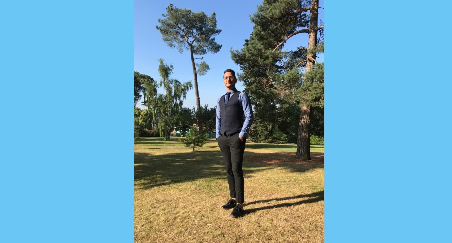 Student stands in front of tree