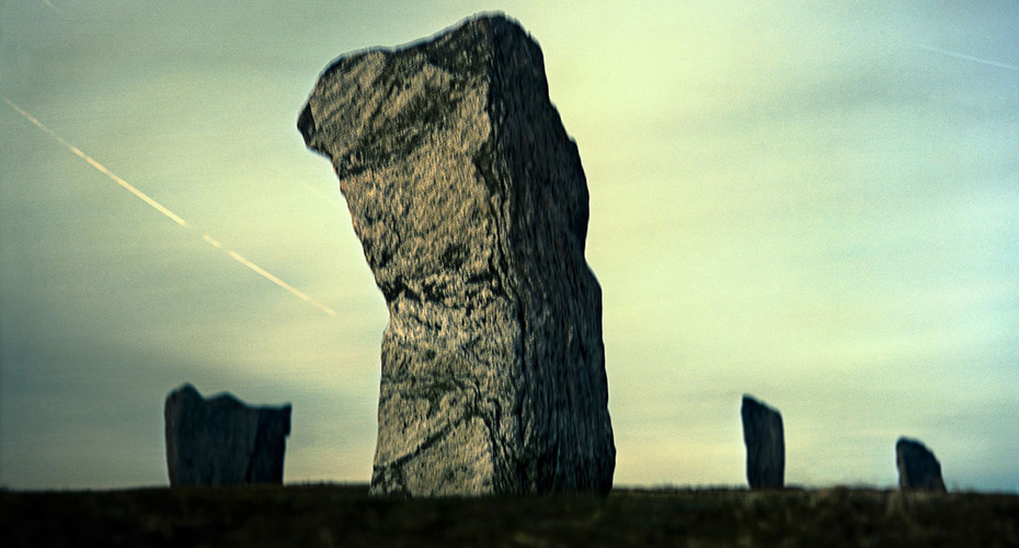 A photograph of large, standing stones at Callanish under a cloudy sky. The central stone is prominently featured, with several smaller stones visible in the background. The scene has a mystical and ancient atmosphere, with a long exposure capturing light trails in the sky.