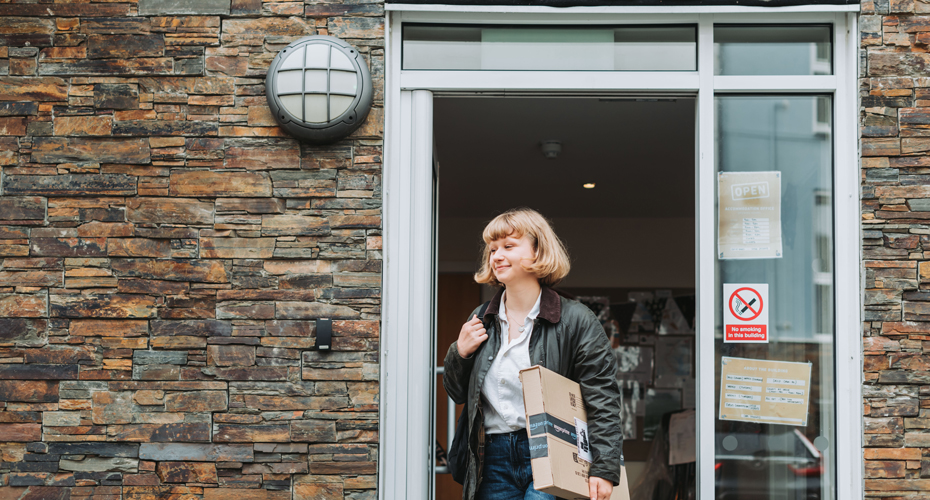 Student walking out of office with Amazon parcel