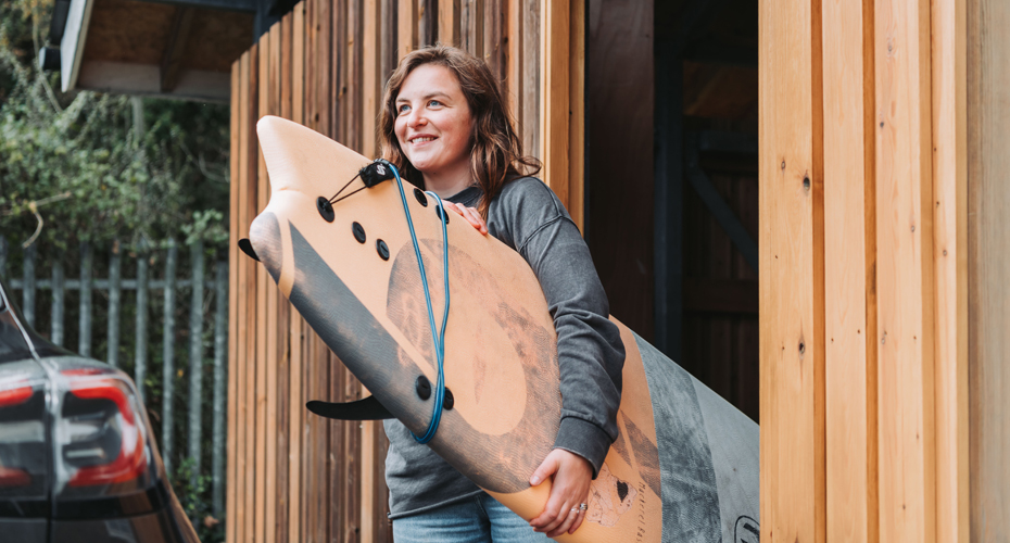 female student carrying orange surfboard