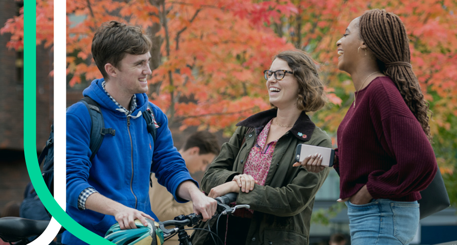 Three students engaged in conversation on a street.