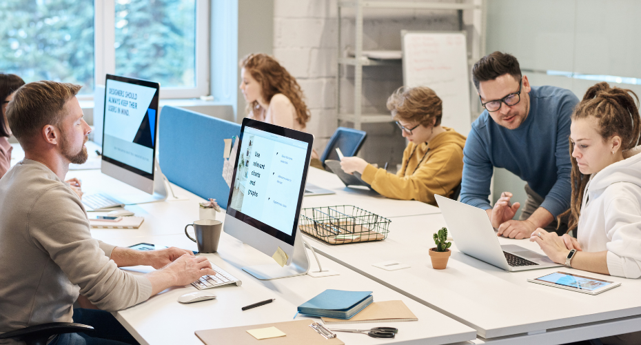 Scene of a group of people sitting at desks, working at computers